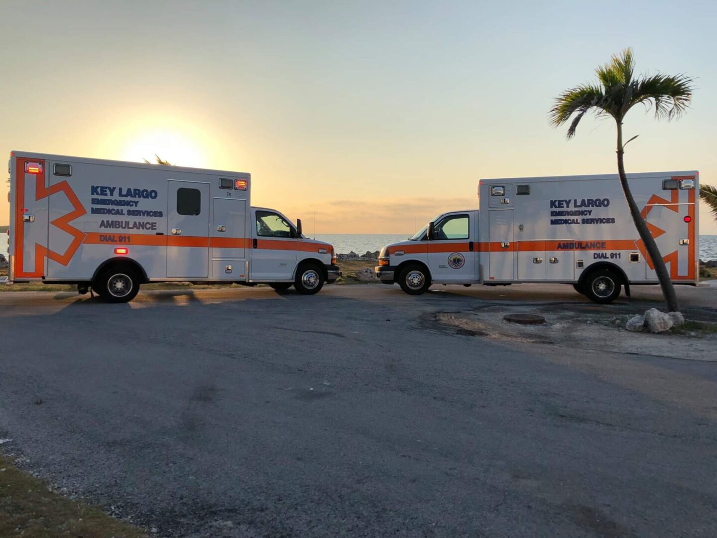 Two ambulances parked in a parking lot near the ocean.